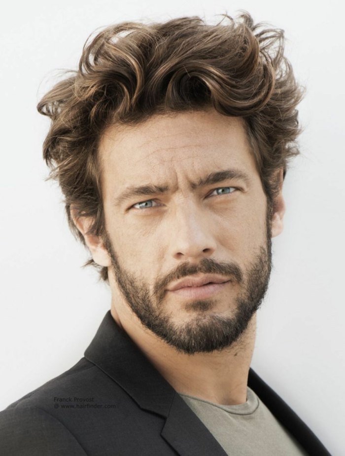 längere Frisurentrends 2020 für Männer, dunkelblonde Haare, Mann mit blauen Augen, kurzer Bart, schwarze Jacke