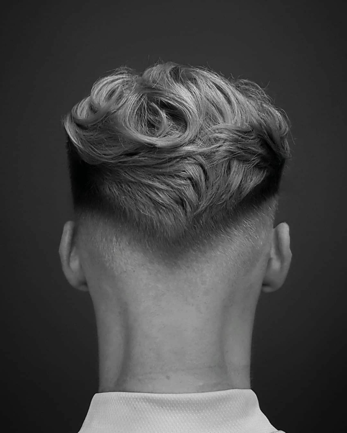 Frisurentrends 2020, Mann mit blonden leicht gewellten Haaren und Undercut Haarschnitt, schwarz weißes Foto, 