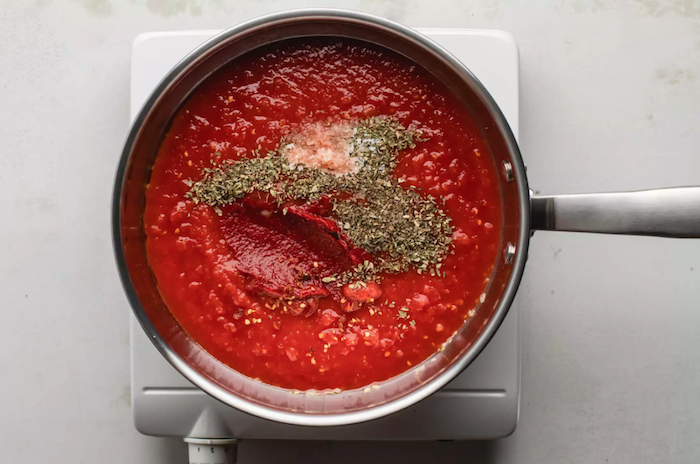 eine herdblatte und ein topf mit tomatensoße mit gewürzen wie kann man tomaten einkochen anleitung