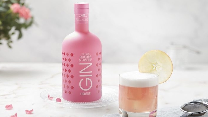 eine pinke flaschecocktails mit gin ein glas mit zitrone und mit dem cocktail pink lady