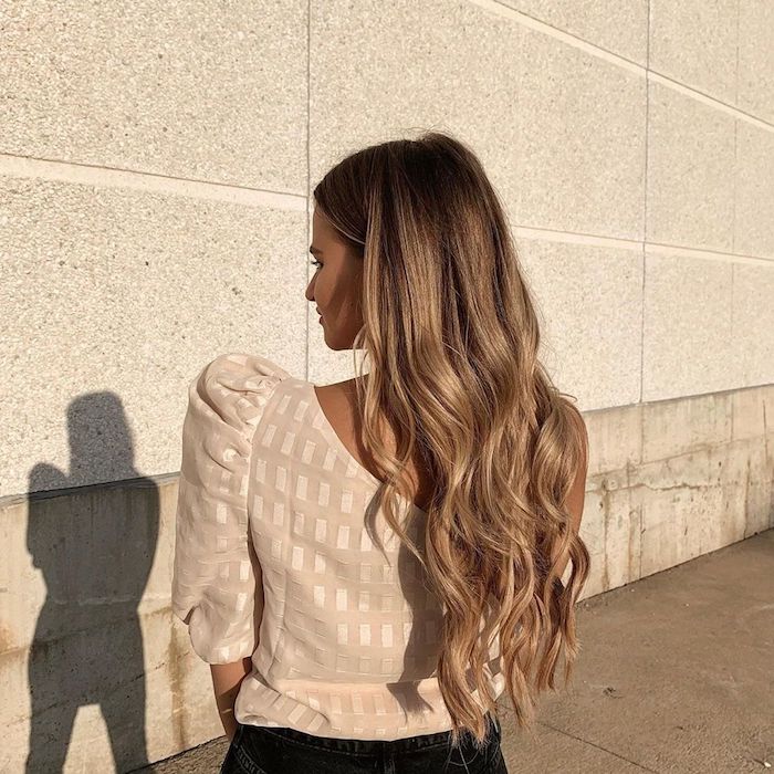 eleganter street style beige bluse schwarze jeans lange gewellte haare braune haare mit blonden strähnen