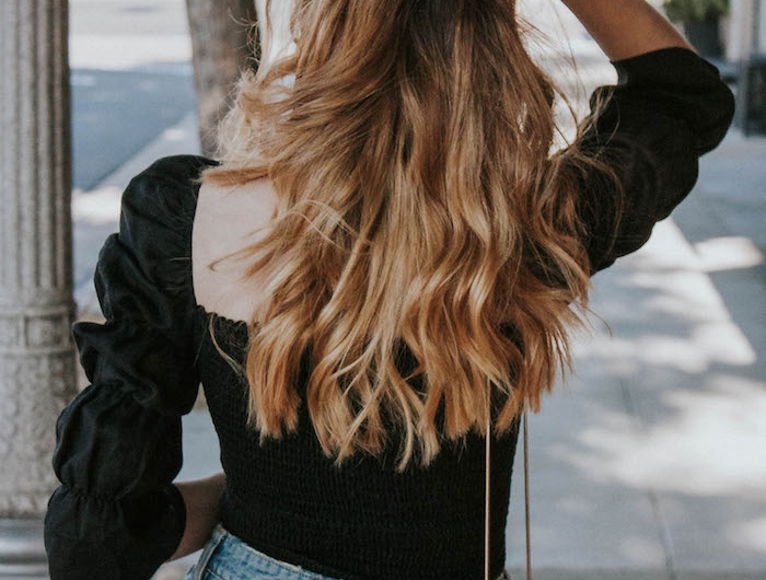 frisuren lange haare blond mit wellen casual outfit schwarze bluse und jeans mini tasche modernes styling
