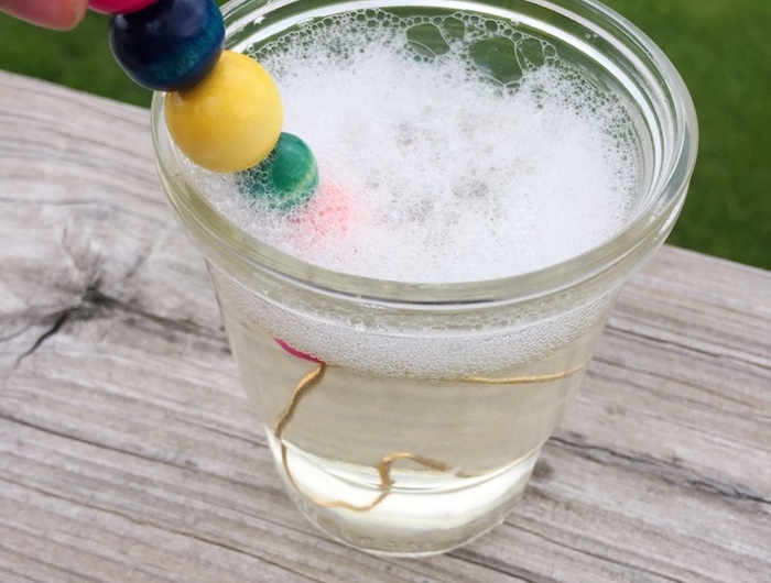 glas mit flüssigkeit für seifenblsen seifenblsen selber machen diy anleitung stabile seifenblasen rezept ein ast mit bunten perlen