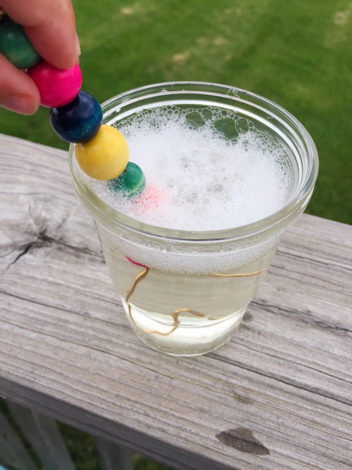 glas mit flüssigkeit für seifenblsen seifenblsen selber machen diy anleitung stabile seifenblasen rezept ein ast mit bunten perlen