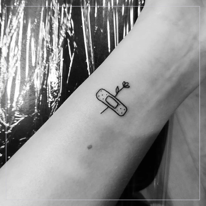 kleine tattoos mit bedeutung tattoo von einer rose und einem pflaster am handgelenk minimalistisces design