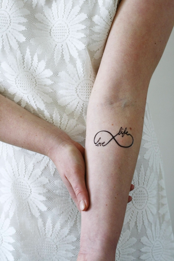 love life mini tattoo mit bedeutung unendlichkeitssymbol frau im weißen kleid mit blumen