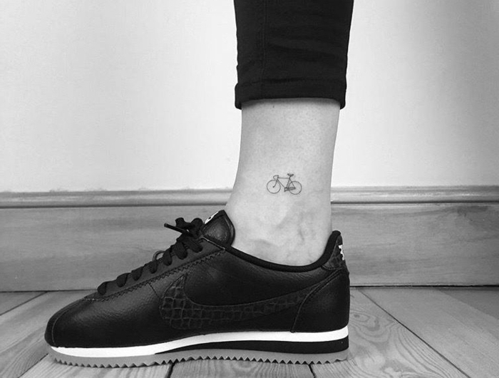 mini tattoo auf dem fußgelenk von einem fahrrad schwarze jeans und sneakers schwarz weißes foto minimalistische tattoos