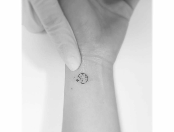 schlichte kleine tattoos handgelenl von der erde und einem fliegenden flugzeug minimalistisches tattoo design