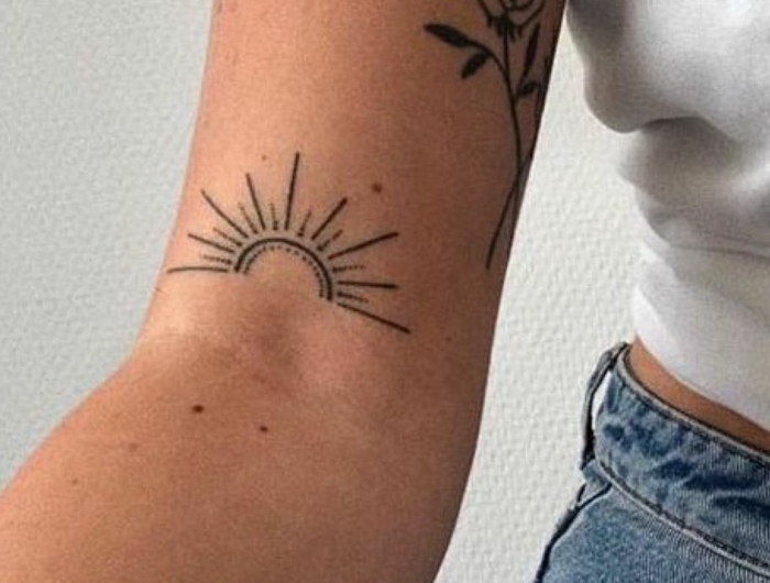 schöne tattoos für frauen tattoo von einer rose und einer aufstehenden sonne blaue jeans weißes t shirt outfit