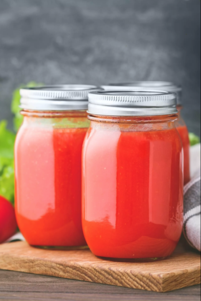 vier große gläser mit sauce ais frischen tomaten einkochen wie kann man tomaten einkochen rezepte ein schneidebrett aus holz