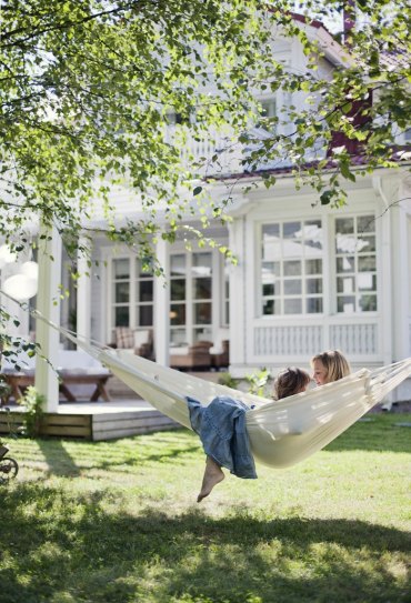 weißes haus mit großem garten moderne gartengestaltung kinder liegen in einer hängematte