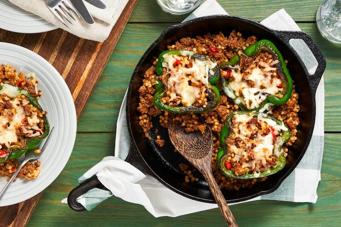 wie kocht man gefüllte paprika vegetarisch rezept ein tisch aus holz und grüne paprika mit couscous