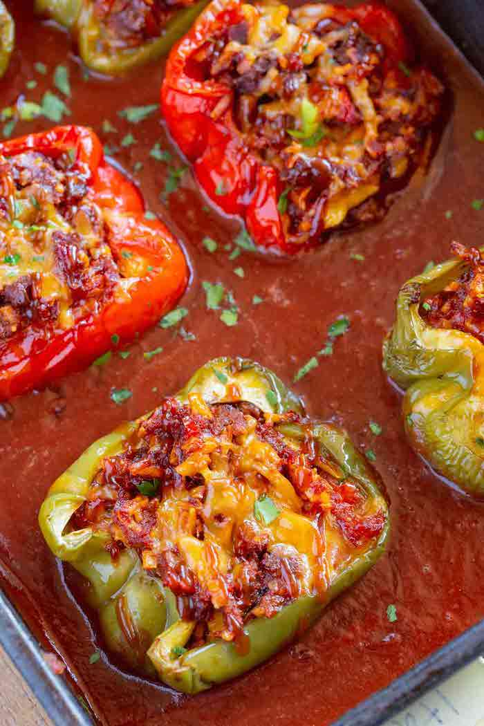 wie macht man gefüllte paprika ein topf mit roter tomatensoße und grüne und rote paprikaschoten mit hackfleisch un petersilie