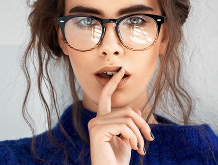 aktuelle brillenmode dickes brillengestell schwarz und braun hochgesteckte gewellte braune haare blauer oversized pullover