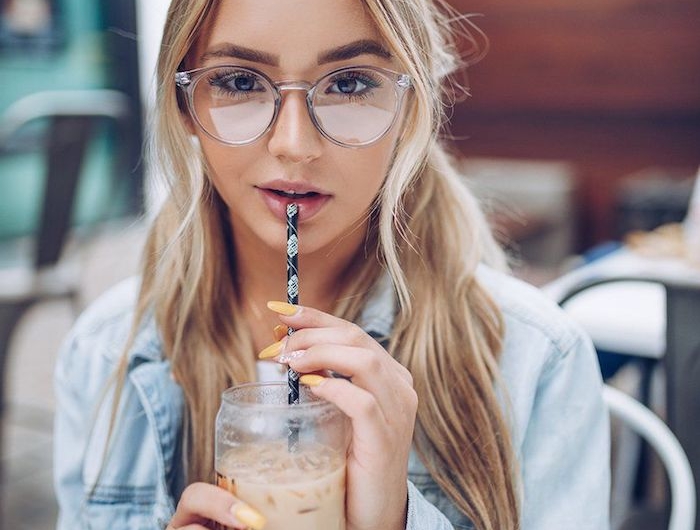 blonde frau mit zwei zöpfen casual style blaue jeansjacke minimalistisches make up durchsichtige modische brille gelber nagellack