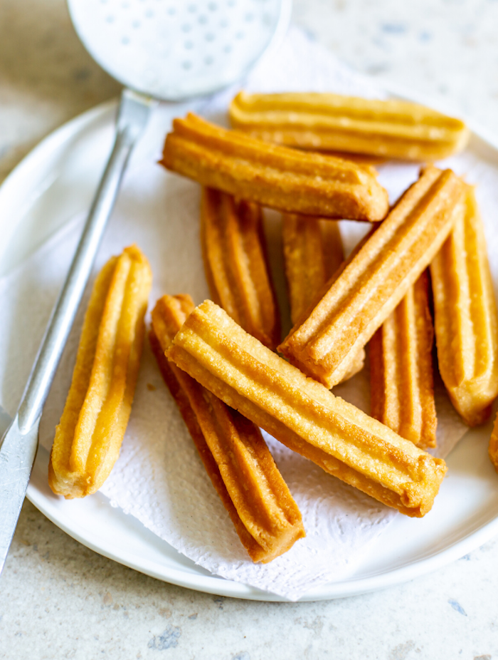 ein churros rezept löffel und ein weißer teller mit langen spanischen churros rezept für nachspeisen