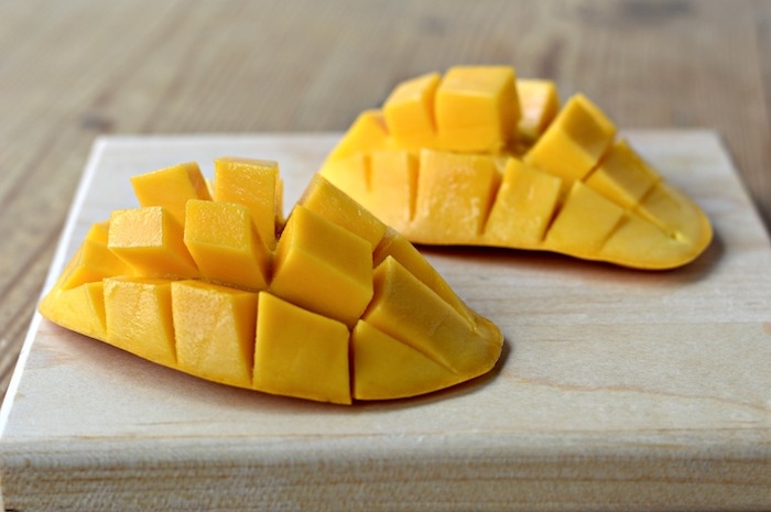 ein holzbrett und zwei große orange mango igel wie kann man eine mango schneiden