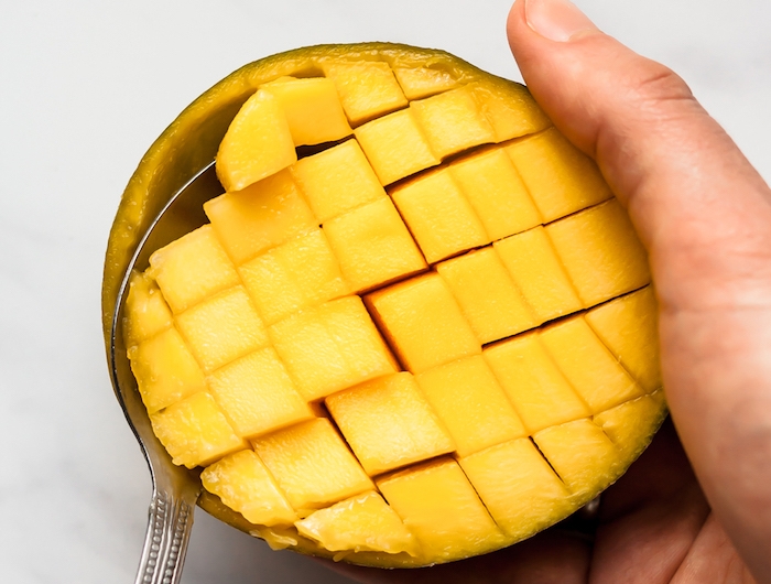 ein löffel und eine geschnittene mango wie kann man eine mango schneiden anleitung