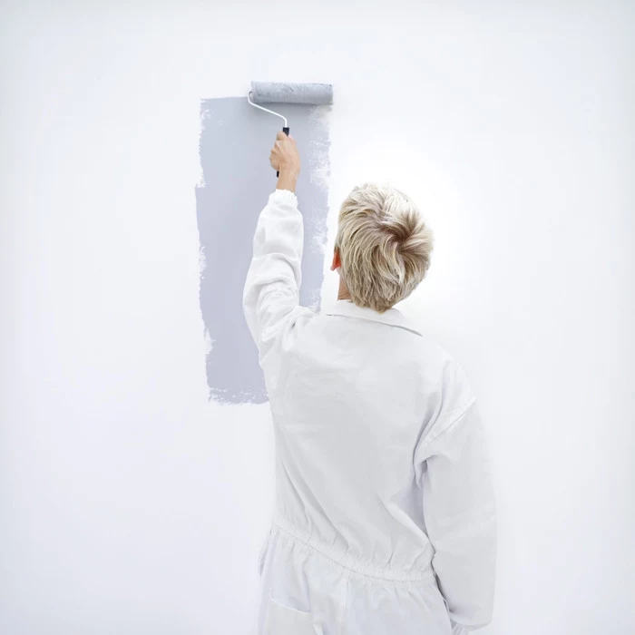 woman painting a wall with a paint roller