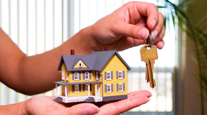 eine hand und schlüssel tipps zum schnellen immobilienverkauf ein gelbes haus