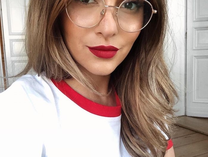 frau mit braunen haaren mit blonden strähnen rot weißes t shirt moderne brillen damen trends 2020 runde brillengestelle dezentes make up roter lippenstift