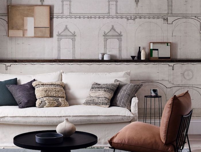 gedämpfte farbpalette wohnzimmer braun roter stuhl weißer couch bunte kissen schwarzer runder kaffeetisch zeichnugn an der wand