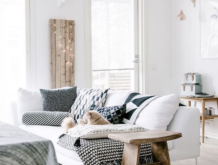 gemütliche und schicke inneneinrichtung in weißen farben mit holzmotiven weißer couch mit dunklen kissen skandinavisches design interior