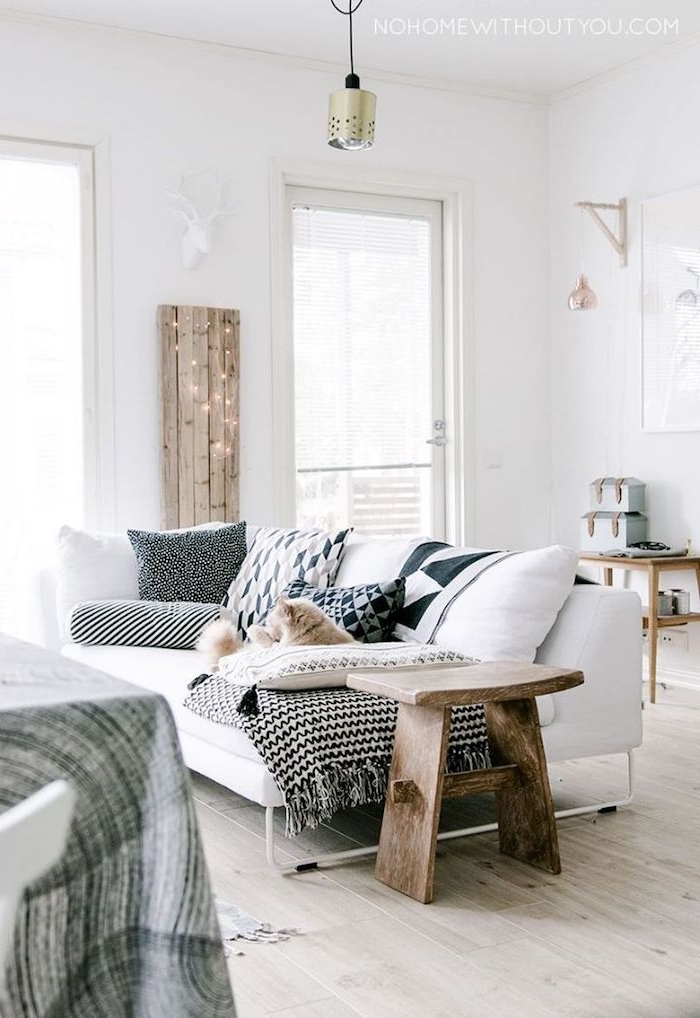 gemütliche und schicke inneneinrichtung in weißen farben mit holzmotiven weißer couch mit dunklen kissen skandinavisches design interior