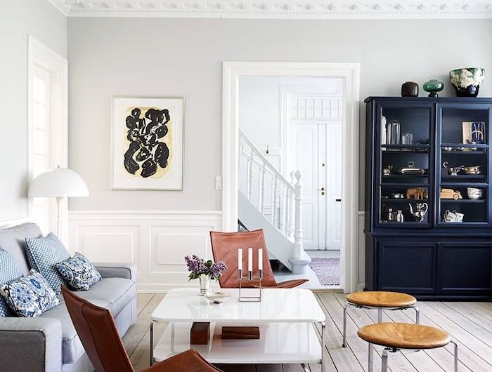 großer schrank in dunkelblau braun rot farbene stühle grau blauer couch weiße wände holzboden schwedische möbel wohnzimmer im skandinavischen stil einrichten