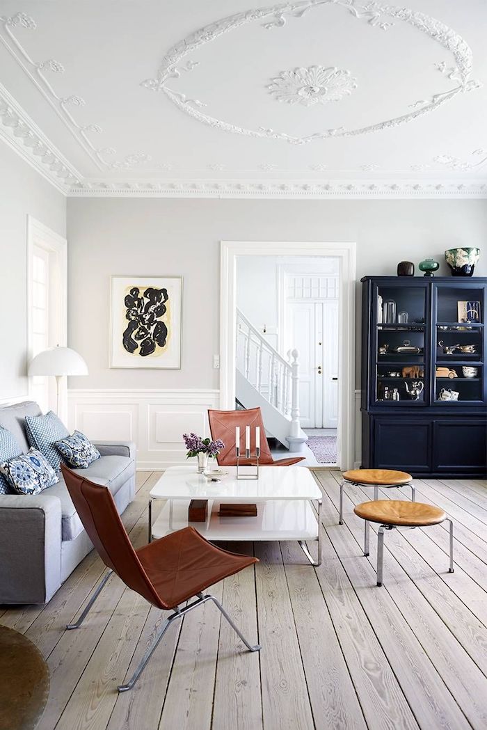 großer schrank in dunkelblau braun rot farbene stühle grau blauer couch weiße wände holzboden schwedische möbel wohnzimmer im skandinavischen stil einrichten