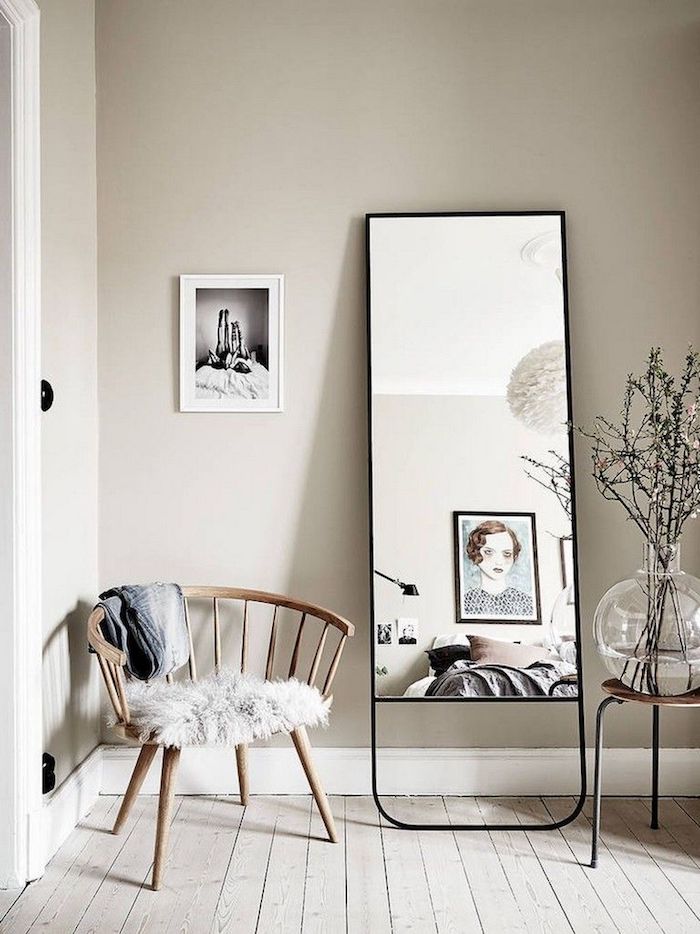 großer spiegel mit schwarzem rahmen wandfarbe neutrale farben skandinavisches wohnzimmer runde vase mit zweigen holzstuhl interior design inspiration ideen