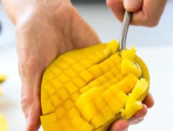 hände eines mannes wie kann man eine mango schneiden hand mit einem löffel