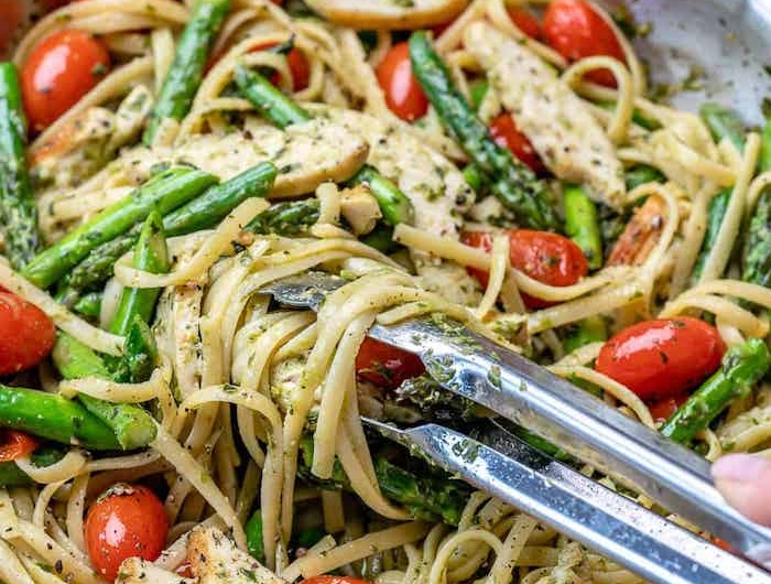 pasta mit spargeö eine pfanne mit pasta mit roten tomaten grünne spargeln und pfeffer
