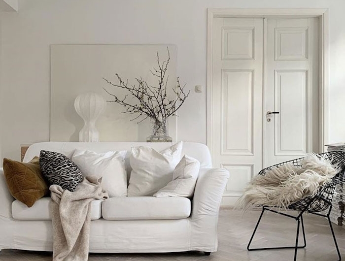 skandinavische einrichtung weiße farbtöne moderner schwarzer stuhl scandi sofa minimalistische inneneinrichtung vase mit zweigen dekoration
