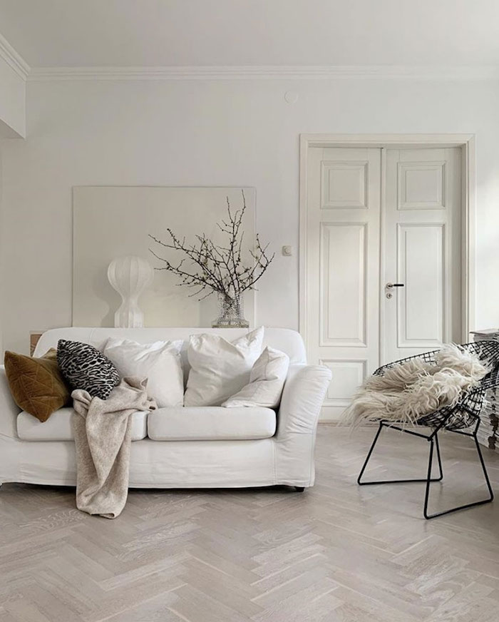 skandinavische einrichtung weiße farbtöne moderner schwarzer stuhl scandi sofa minimalistische inneneinrichtung vase mit zweigen dekoration