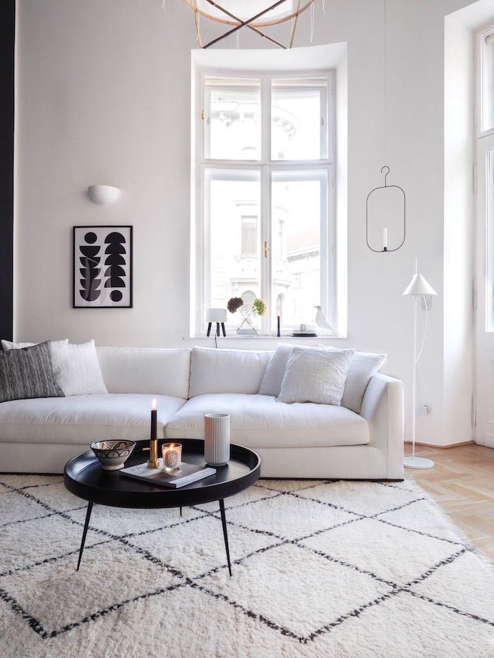 skandinavischer teppich unter weißem sofa und schwarzem couchtisch mit drei beinen schwarz weißes bild dekoration ideen deko skandinavisch