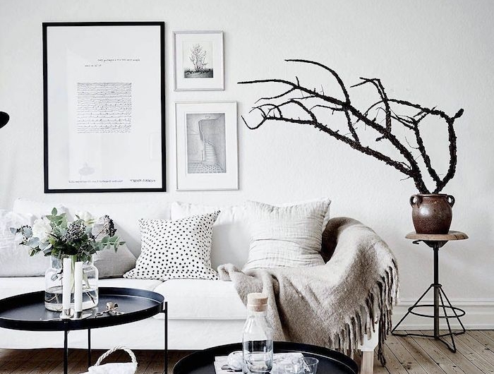 skandinavisches design zwie runde kaffeetische grauer teppich holzakzente weiße wände minimalistische bilder deko baum minimalistische einrichtung wohnzimmer
