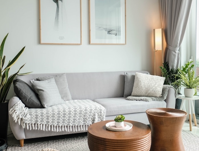 skandinavisches wohnzimmer im minimalistischen stil grauer sofa mit holzbeinen kleine kaffetische teppich in beige