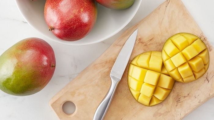 tisch und grope reife mangos ein scharfer messer und ein holzbrett zwei mango igel