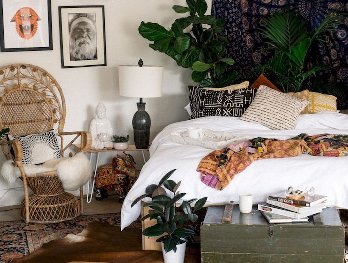 boho chic style einrichtung schlafzimmer bilder an die wand großer schwarzer wandteppich grüne pflanzen deko kissen korbstuhl vintage einrichtung
