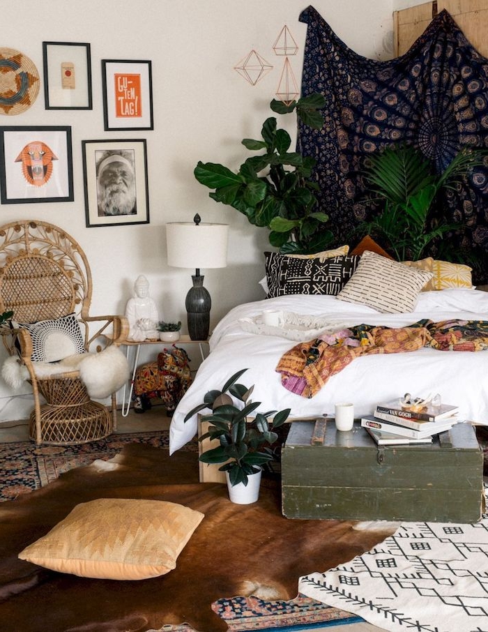 boho chic style einrichtung schlafzimmer bilder an die wand großer schwarzer wandteppich grüne pflanzen deko kissen korbstuhl vintage einrichtung