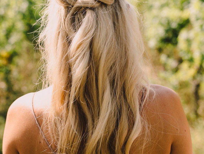 brautjunger flechtfrisuren halboffen lange blonde haare mit leichten wellen elegantes braunes kleid grünes blatt im haar accessoire boho chic hochzeit