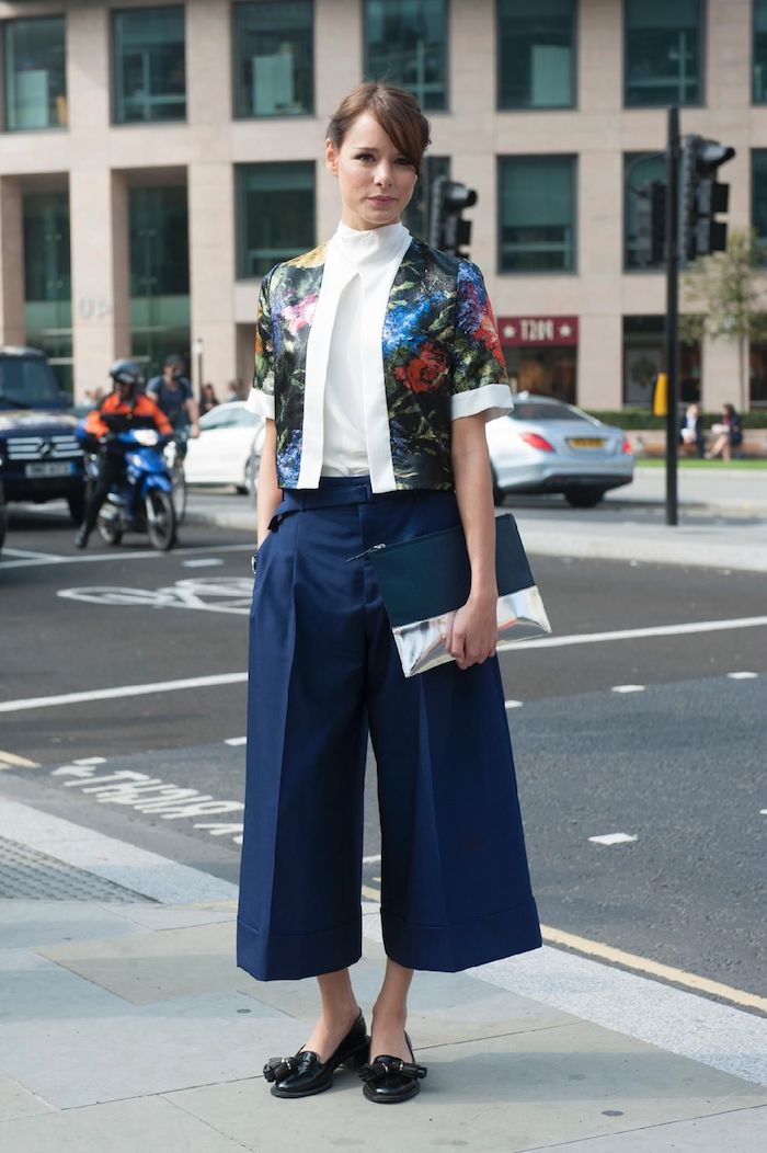 business casual style für dame blaue culotte hose kombinieren kurze bunte jacke mit blumen muster schwarze schuhe elegantes clutch weiße bluse