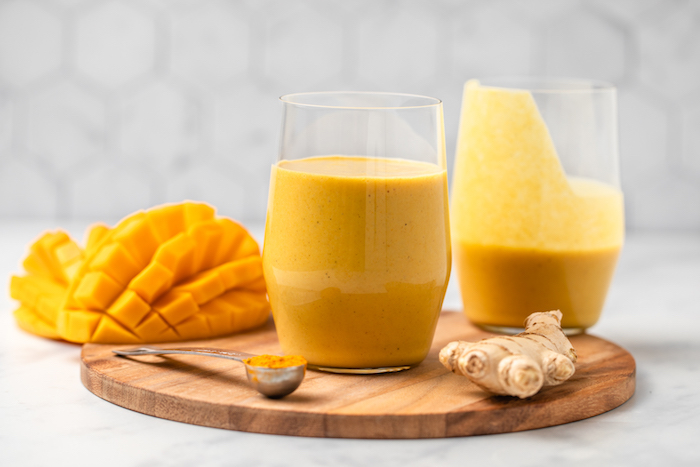 ein brett aus holz rezept für ein glas goldene milch mit inwer kurkuma und mango ein löffel