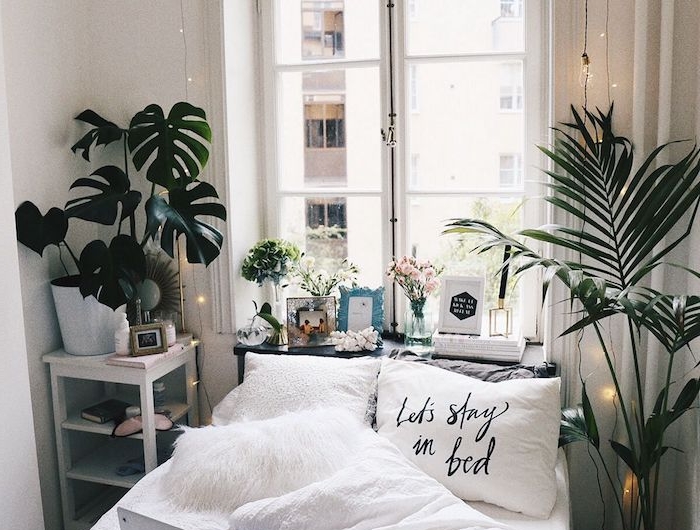 gemütliches kleines schlafzimmer design dekoration grüne pflanzen weißer kissen mit abdruck teenager zimmer mädchen dekorierte fensterbank aufgehängte lichterketten