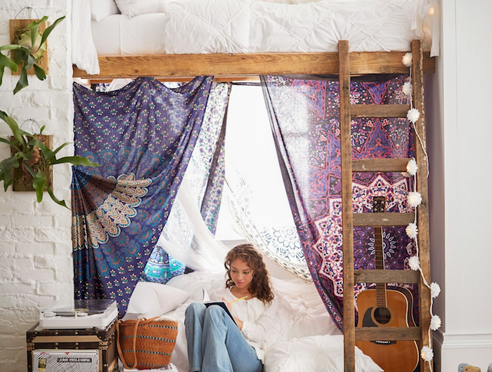 hippie style inneneinrichtung hochbett jugendzimmer mit leiter geometrischer teppich boho chic inneneinrichtung junges mädchen schreibt im heft bunte bettvorhänge