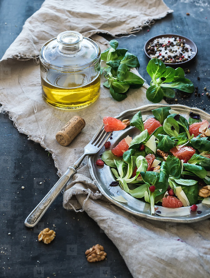 löffel und ein teller mit feldsalat die zutaten für salat mit feldsalat nüssen eine weiße decke ist feldsalat gesund