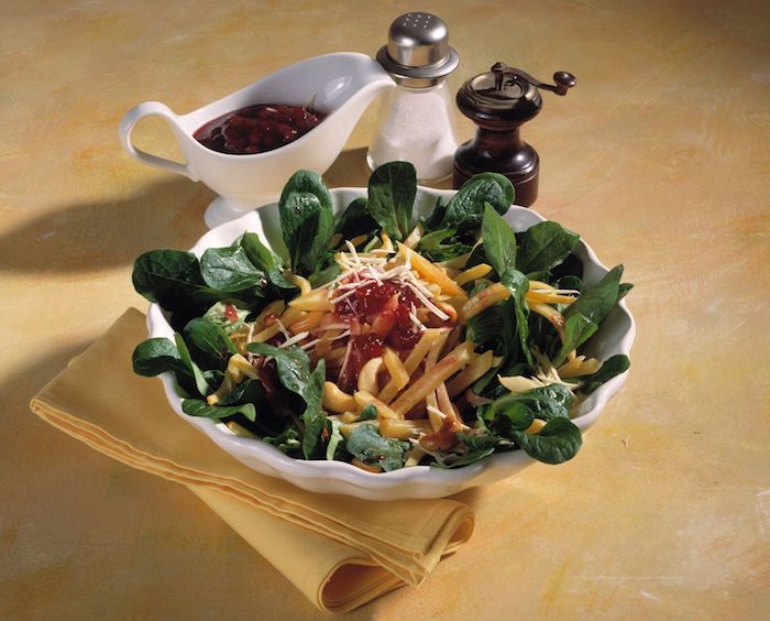 pfeffer und salz eine weiße schüssel mit salat mit käse tomatensauce und mit grünne blettern eines feldsalats