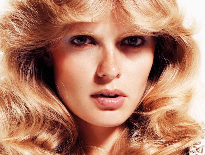 retro frisur aus den 70 er frau mit mittellangem welligen haar blond auf weißem hintergrund