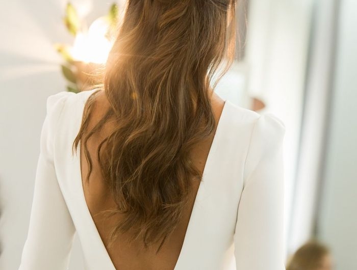 rückenloses weißes kleid mit langen ärmeln lange gewellte braune haare brautfrisuren 2020 haaraccessoires tiara mit gold und perlen hochzeitsfeier